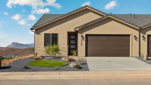 View of front of house with a garage, stucco siding, driveway, stone siding, and a mountain view