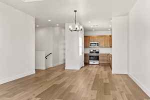 Kitchen with stainless steel appliances, light wood finished floors, a chandelier, light countertops, and recessed lighting