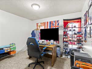 Carpeted home office featuring a textured ceiling