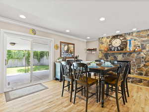 Dining room with ornamental molding, wood finished floors, recessed lighting, and a stone fireplace