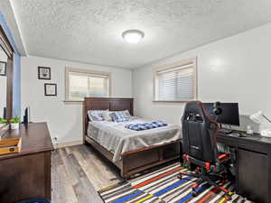 Bedroom featuring wood finished floors, a textured ceiling, and an office area