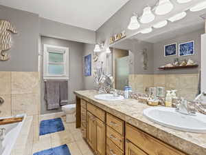 Full bathroom with a stall shower, double vanity, tile patterned floors, a garden tub, and tile walls