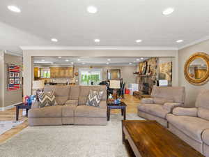 Living area featuring ornamental molding, light wood-style floors, recessed lighting, and a stone fireplace
