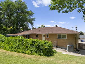 Back of property featuring brick siding, a yard, a patio area, and a shingled roof