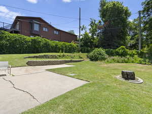 View of grassy yard featuring an outdoor fire pit and a patio area