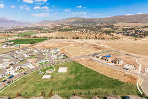 Aerial view of property and surrounding area featuring mountains and nearby suburban area