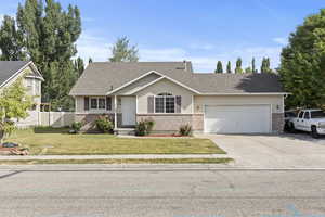 View of front of house featuring a garage, concrete driveway, brick siding, and roof with shingles