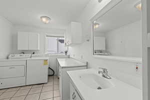 Laundry room with independent washer and dryer, light tile patterned floors, and ornamental molding