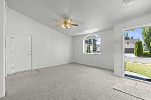Carpeted foyer entrance with lofted ceiling, ceiling fan, and tile patterned floors