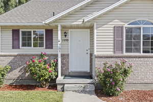Doorway to property with brick siding and a shingled roof