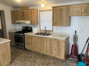 Kitchen featuring stainless steel gas range, under cabinet range hood, light countertops, brown cabinets, and ornamental molding
