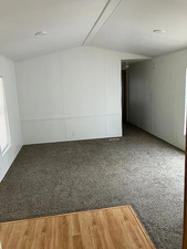 Unfurnished room featuring vaulted ceiling and a decorative wall