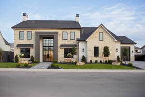 View of front facade featuring a chimney, stone siding, and a front lawn
