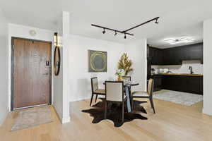 Dining area with light wood-style floors and track lighting