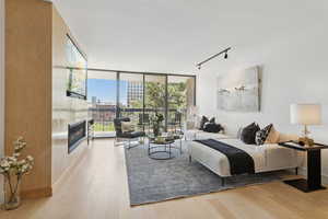 Bedroom with a large fireplace, floor to ceiling windows, rail lighting, access to exterior, and multiple windows