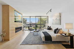 Living room with expansive windows, track lighting, a tile fireplace, and wood finished floors