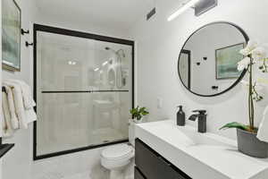 Full bath with vanity, a shower stall, and marble finish flooring