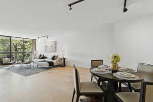 Dining space with track lighting, a wall of windows, and wood finished floors