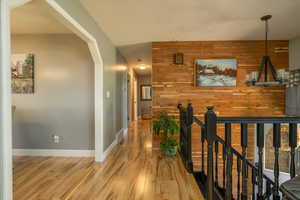 Hall with wooden walls, arched walkways, and light wood-style floors