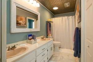 Bathroom featuring double vanity, marble look tile flooring, a shower with shower curtain, and an ornate ceiling