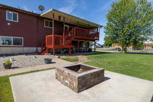 Rear view of house with a fire pit, a patio, a lawn, a deck, and stairway