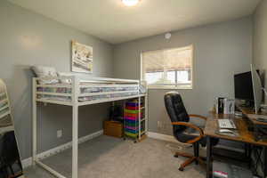 Carpeted bedroom with baseboards and a desk