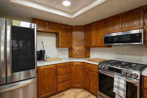 Kitchen with appliances with stainless steel finishes, light countertops, light wood-style floors, and brown cabinets