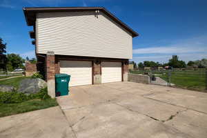 View of property exterior with an attached garage, brick siding, driveway, and a gate