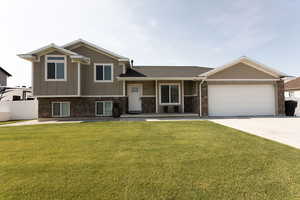 Split level home with an attached garage, driveway, board and batten siding, and a shingled roof