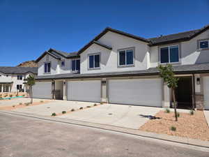 View of front of house featuring an attached garage, stucco siding, driveway, and a tiled roof