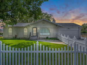 Ranch-style house featuring a fenced front yard, a garage, and brick siding