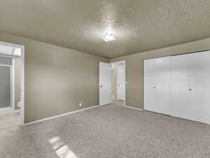 Unfurnished bedroom with a textured ceiling, carpet, and a closet