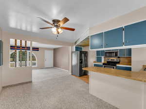 Kitchen featuring appliances with stainless steel finishes, blue cabinetry, a ceiling fan, and light colored carpet