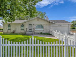 Ranch-style home with a fenced front yard, an attached garage, a chimney, and concrete driveway