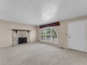 Unfurnished living room with a textured ceiling, carpet, and a fireplace