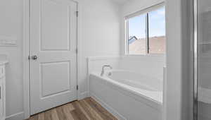 Full bath featuring a garden tub, wood finished floors, and vanity