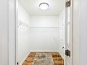 Walk in closet with light wood-type flooring