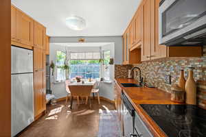 Kitchen featuring appliances with stainless steel finishes, a sink, tasteful backsplash, baseboards, and finished concrete floors