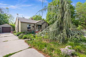 View of front of house featuring stucco siding, an outdoor structure, a garage, concrete driveway, and a chimney