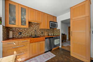 Kitchen with a sink, stainless steel appliances, decorative backsplash, and glass insert cabinets