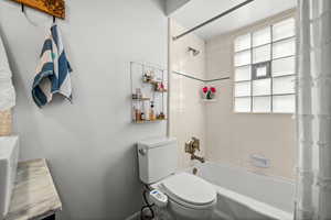 Bathroom with shower / bathtub combination with curtain and toilet