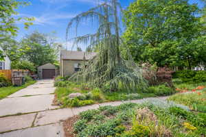 Obstructed view of property with a detached garage, concrete driveway, an outdoor structure, and stucco siding