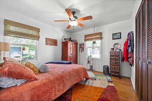 Bedroom featuring wood finished floors, multiple windows, baseboards, and ceiling fan