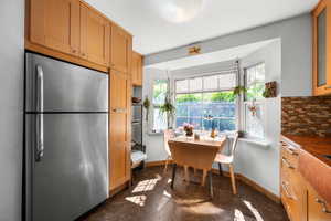 Kitchen with freestanding refrigerator, baseboards, glass insert cabinets, and tasteful backsplash
