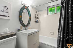 Bathroom featuring shower / tub combo with curtain, toilet, and vanity