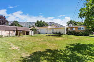 View of green lawn featuring a garage, a mountain view, and a shed