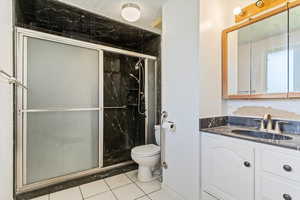 Bathroom featuring vanity, a marble finish shower, and tile patterned floors