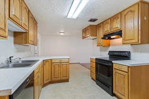Kitchen featuring under cabinet range hood, black range with electric stovetop, dishwashing machine, a textured ceiling, and a peninsula