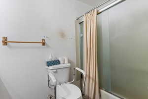 Full bathroom featuring shower / bathtub combination with curtain and toilet