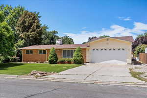 Single story home with a garage, concrete driveway, a front yard, and brick siding